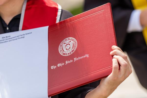 Spring Commencement Ceremony at Ohio Stadium.  OPRES - Office of the President. A graduate displays their Ohio State diploma