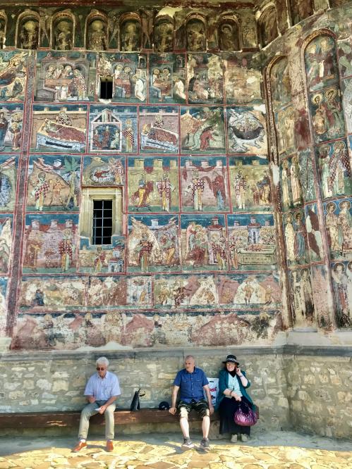 People sitting in front of religious paintings in Romania