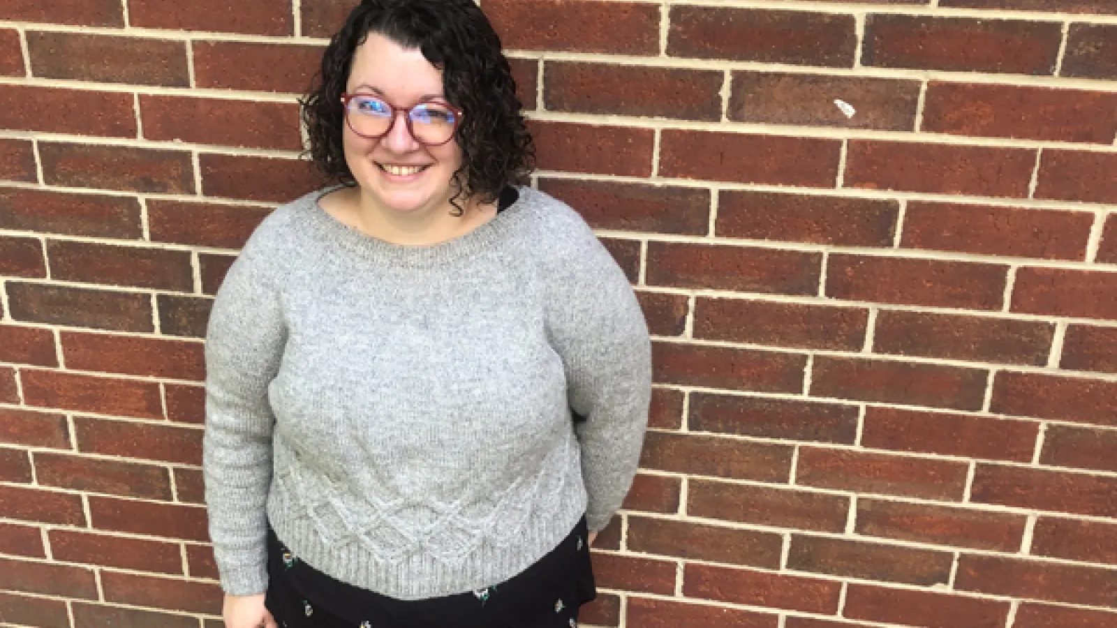 Kate White standing in front of a brick wall.