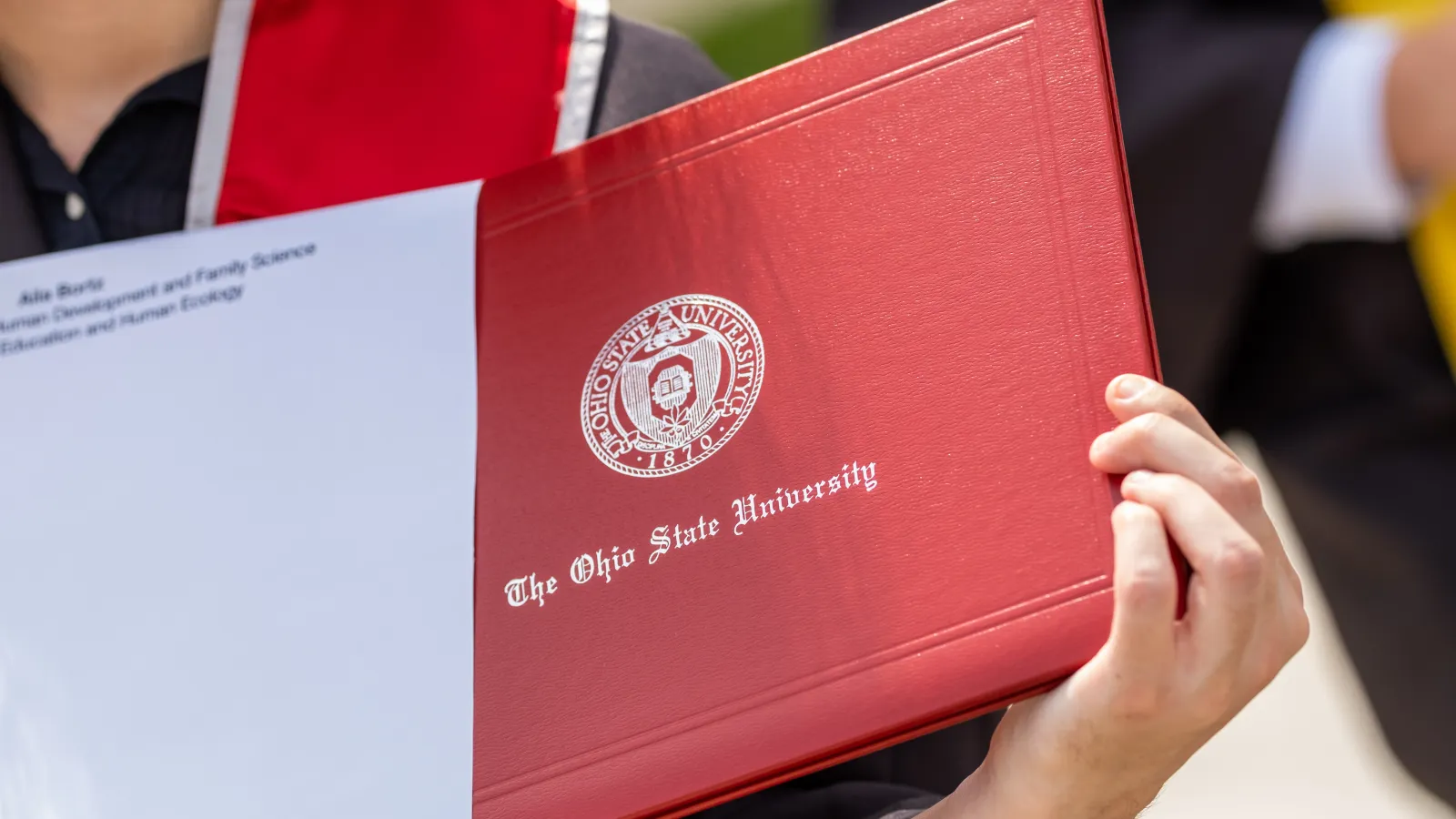Spring Commencement Ceremony at Ohio Stadium.  OPRES - Office of the President. A graduate displays their Ohio State diploma