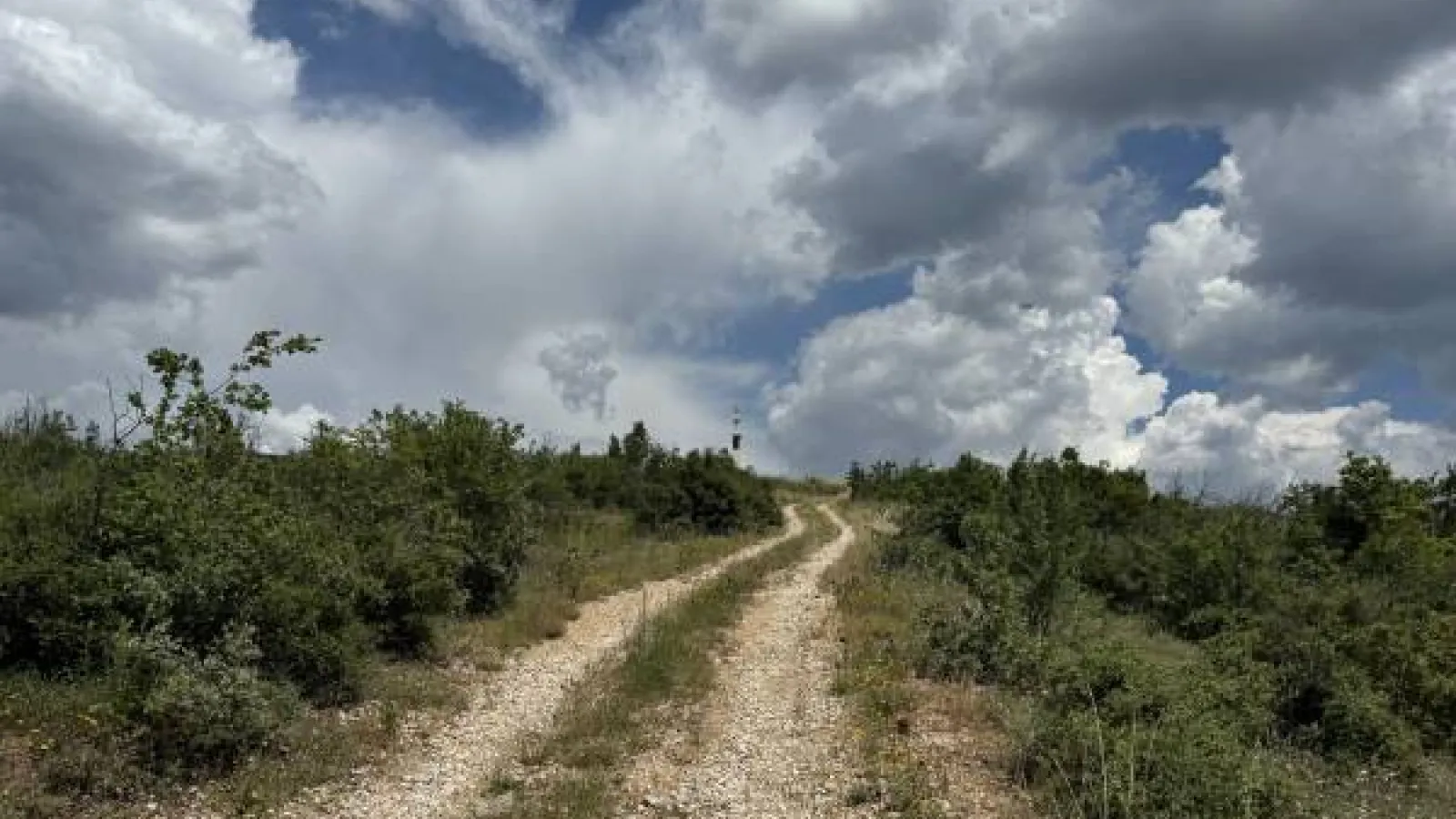 A dirt road leads uphill to dramatic clouds in Bulgaria