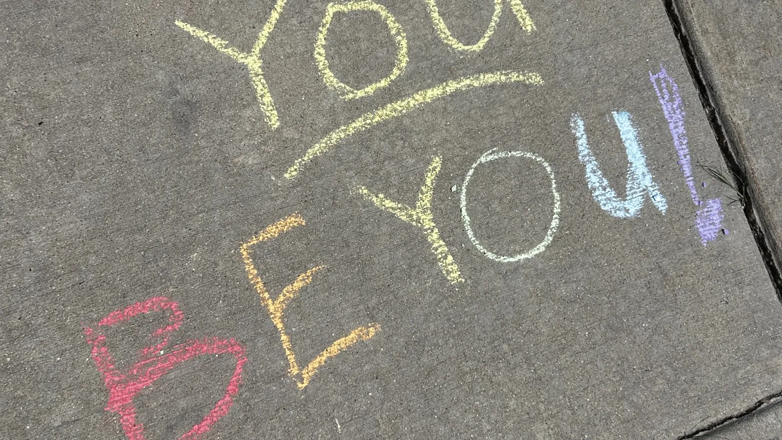 Rainbow chalk writing on the sidewalk that read "You be you!"