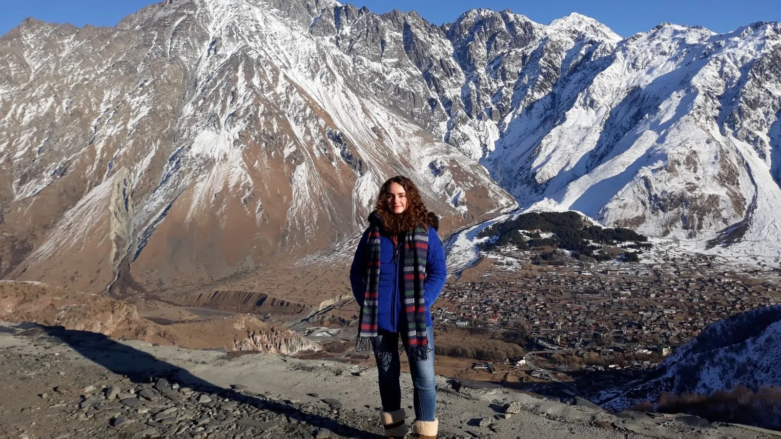 Margot Hare in winter gear stands in front of Mount Kazbegi