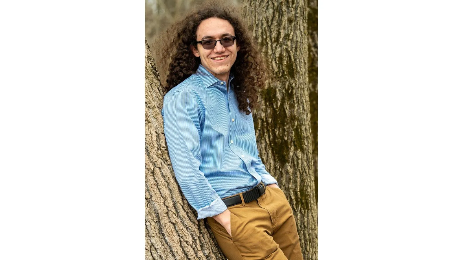 A portrait of Liam Martin leaning against a tree
