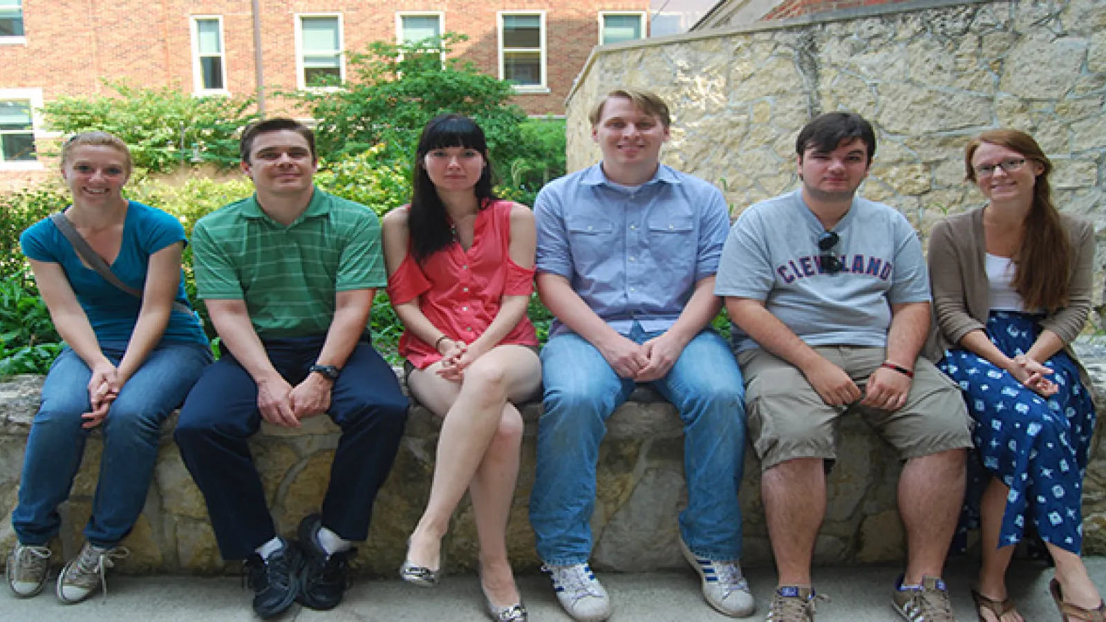 Students sitting on a ledge with garden in background