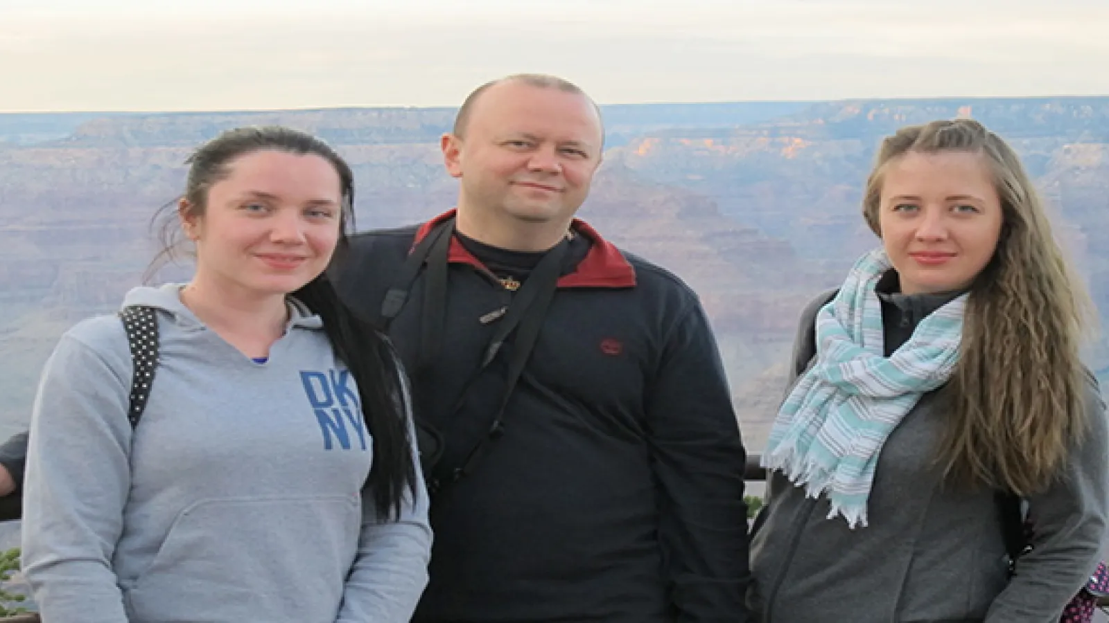 Two women and a man standing next to each other with the Grand Canyon in the background