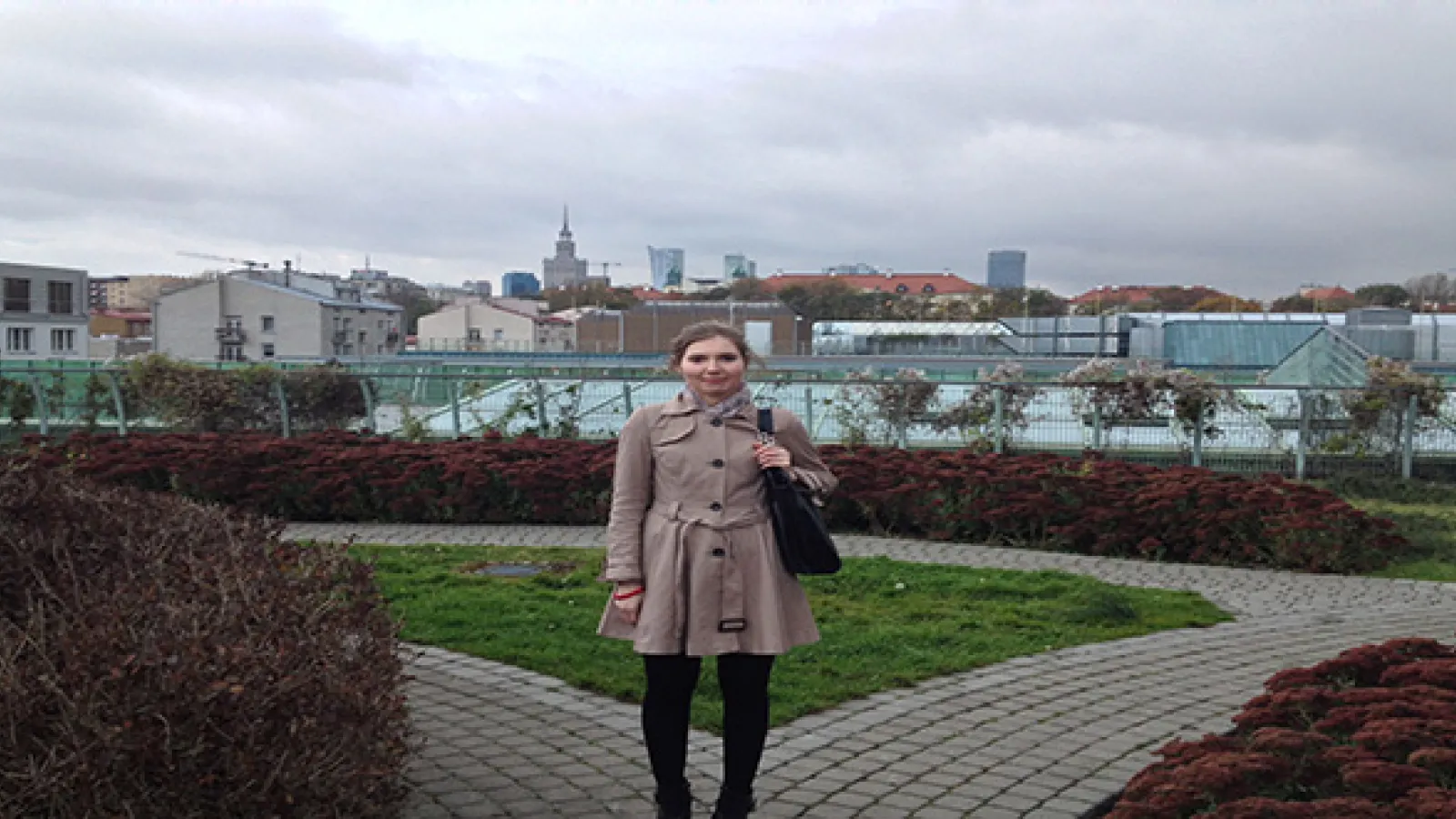 Girl standing in a park with buildings in background