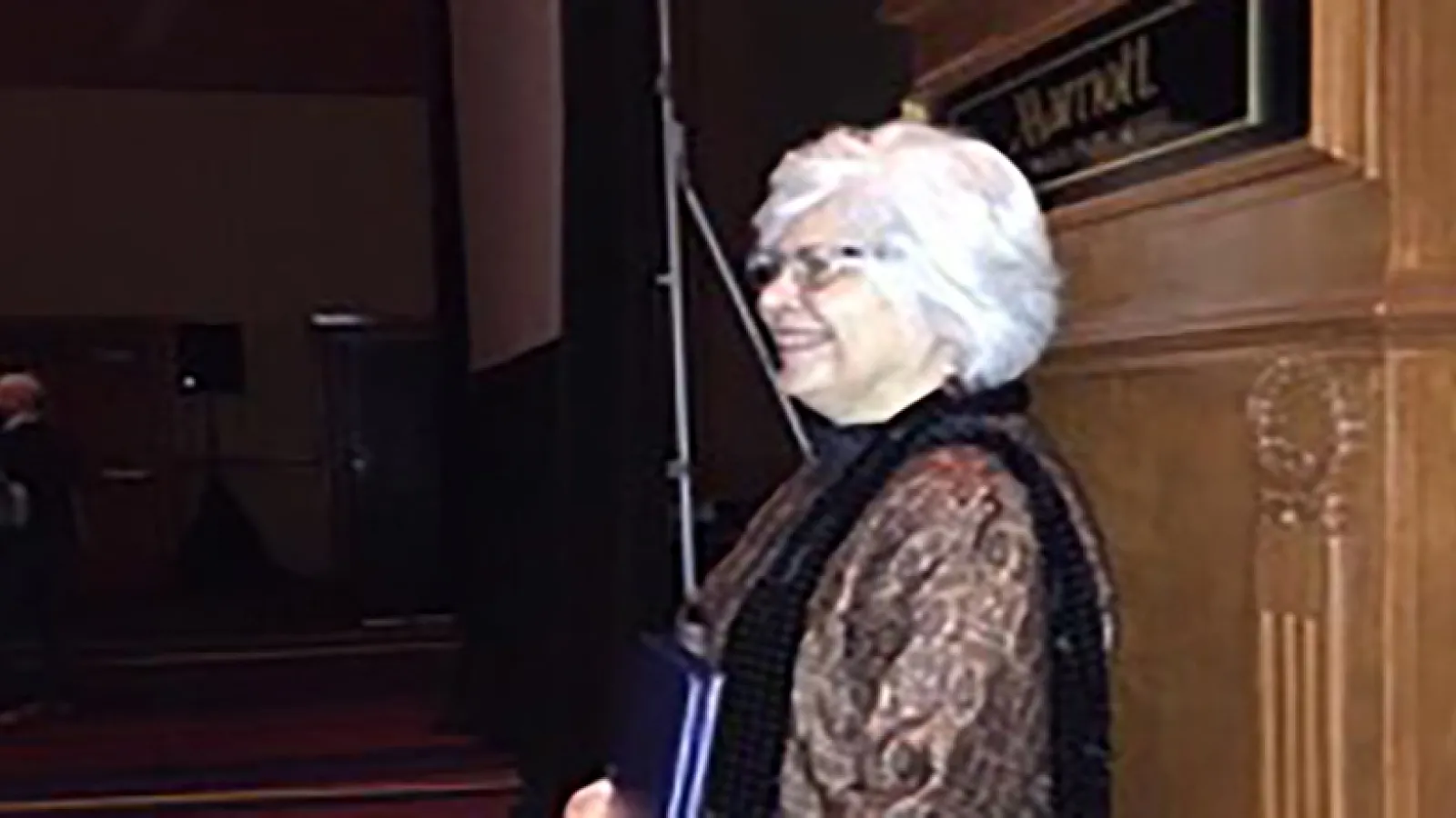 Side view of a woman standing in front of a podium holding an award
