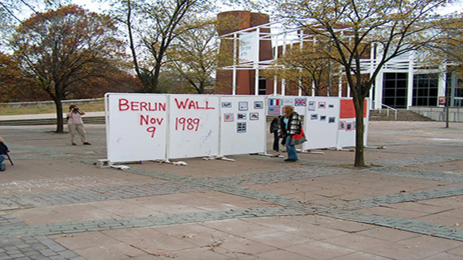White board and pipe wall structure sitting in the middle of a plaza with graffiti