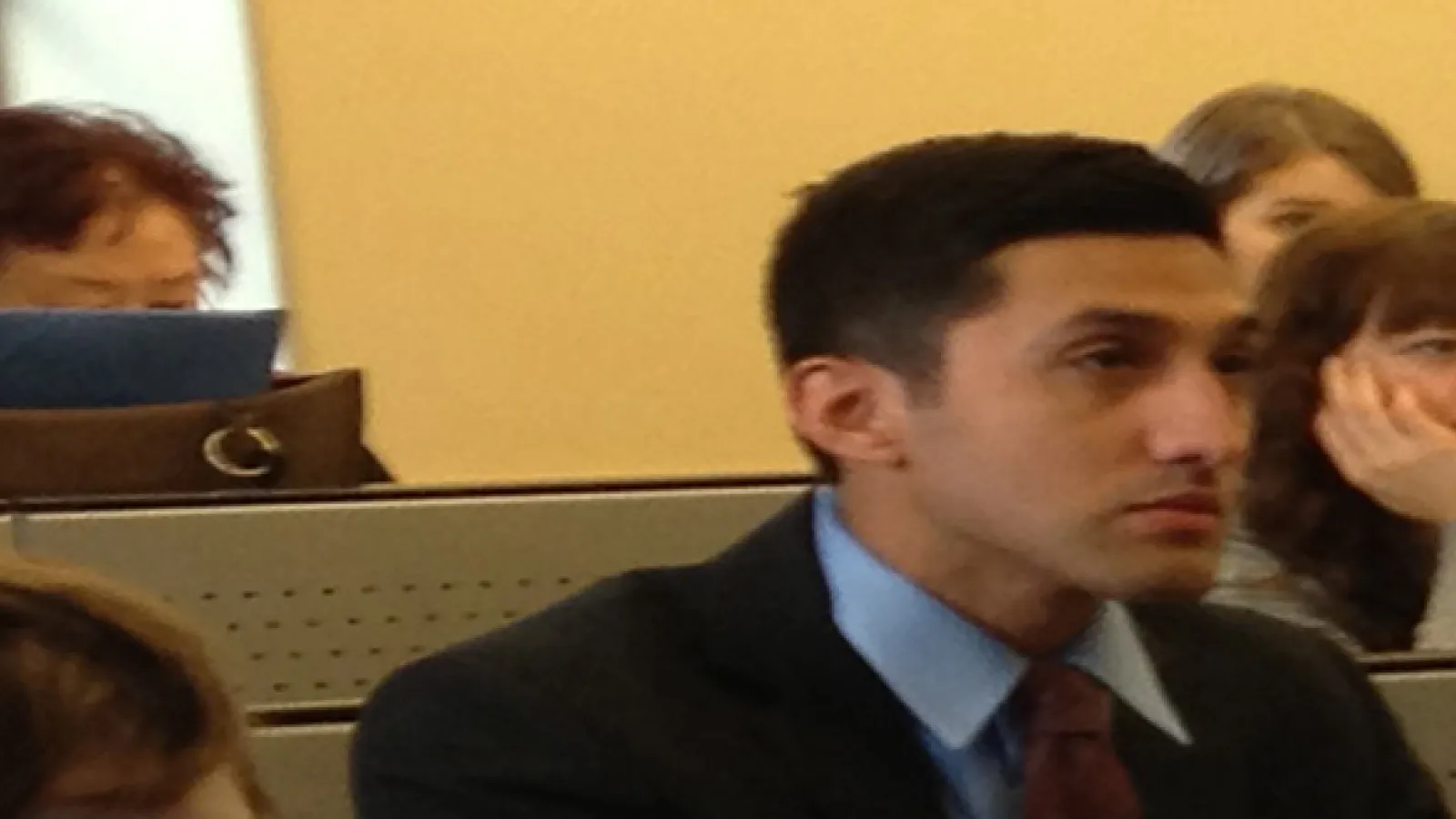 A man's face from the side wearing a suit and tie