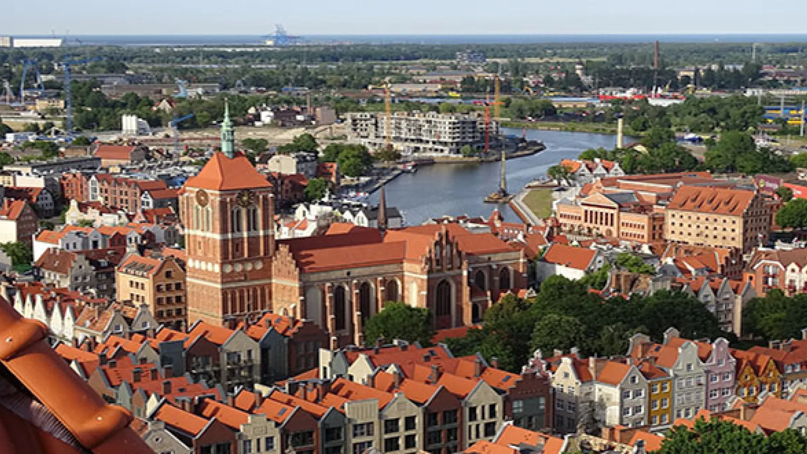 Aerial view of city with red brick buildings with tile roofs, and a river in the background winding through the city