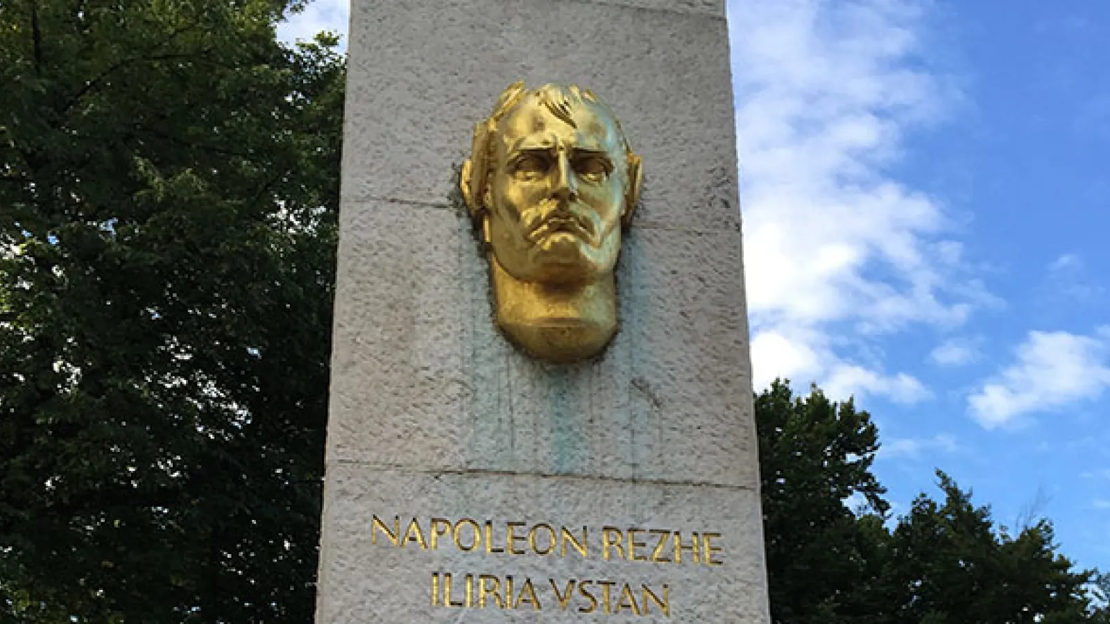 A stone pillar with a golden face and lettering on it