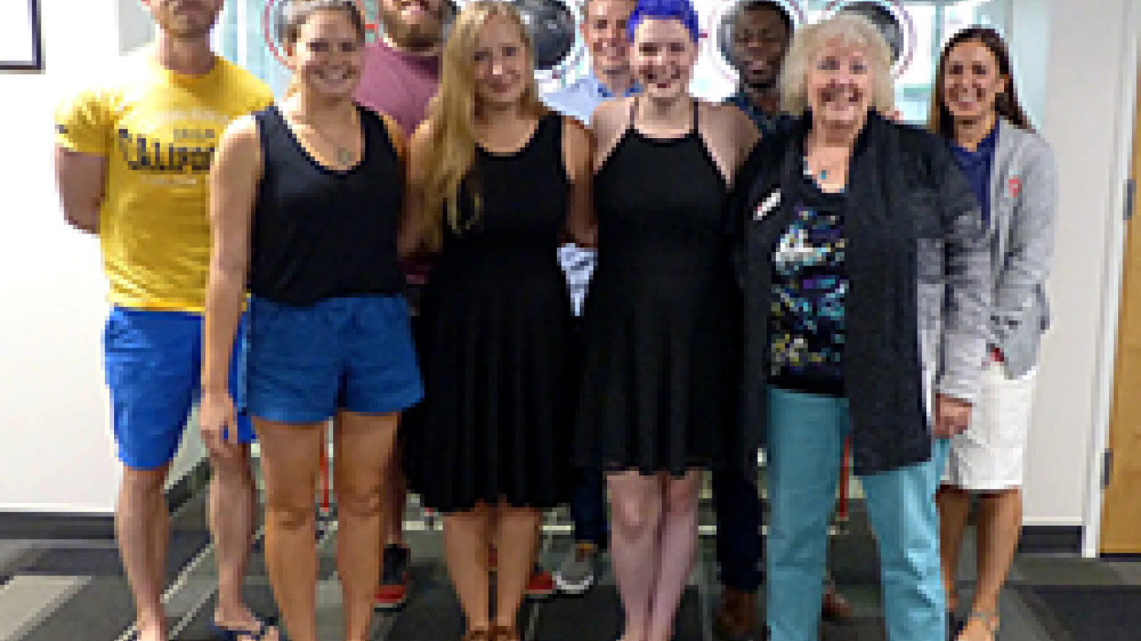 9 people standing in two rows shoulder-to-shoulder