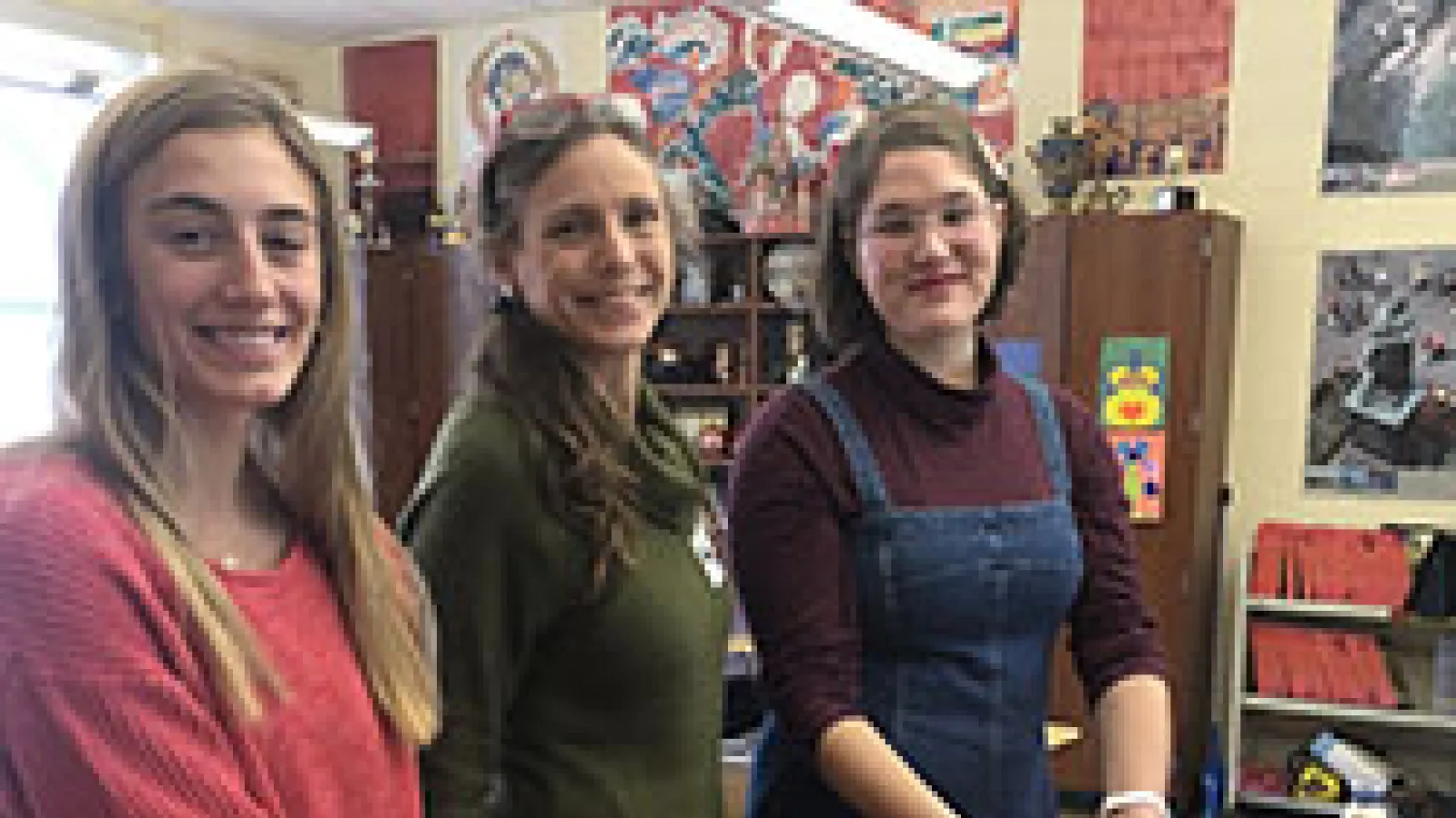 three women standing by a table with a pie on it