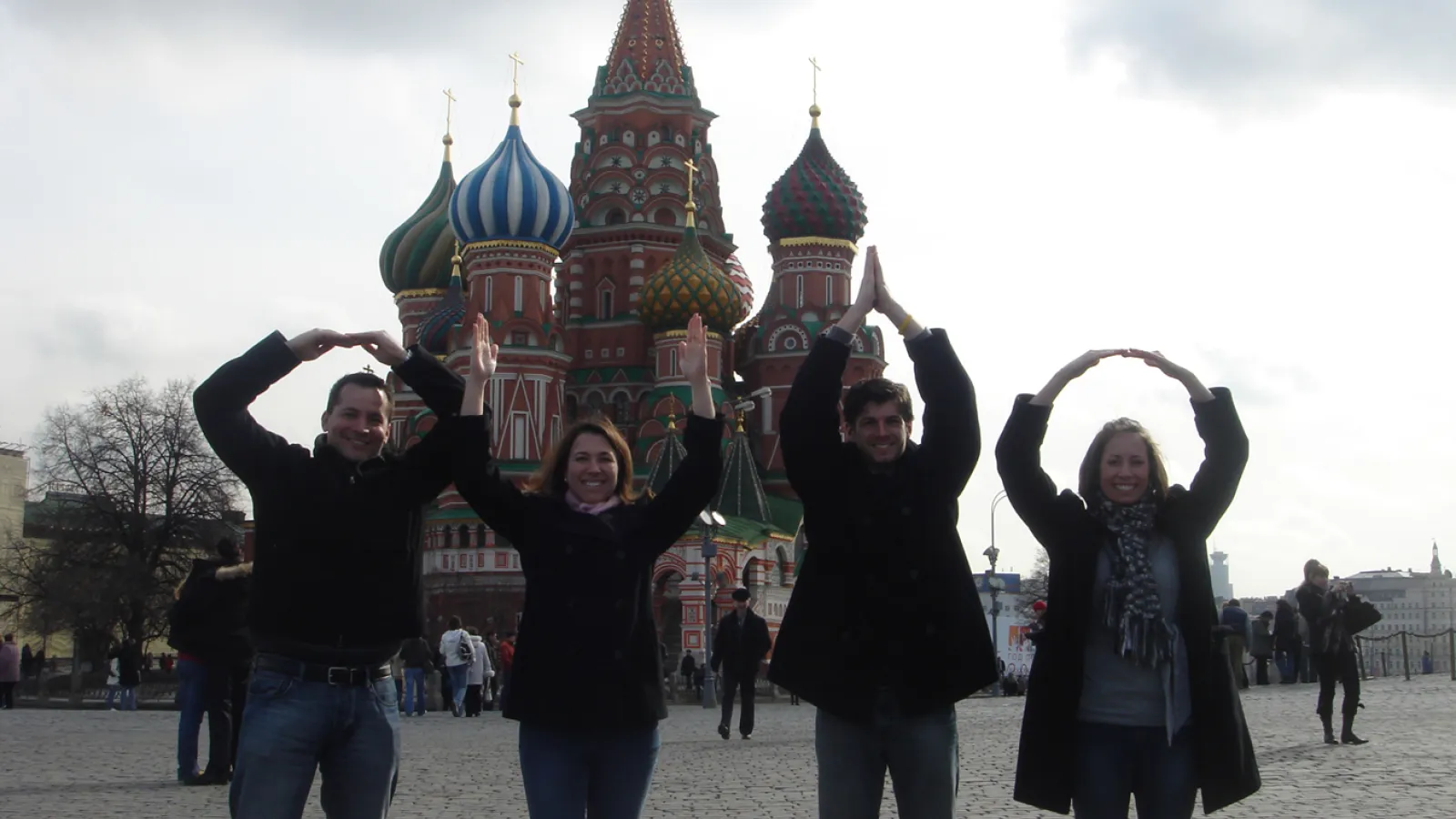 Four people standing on a square spelling out O-H-I-O