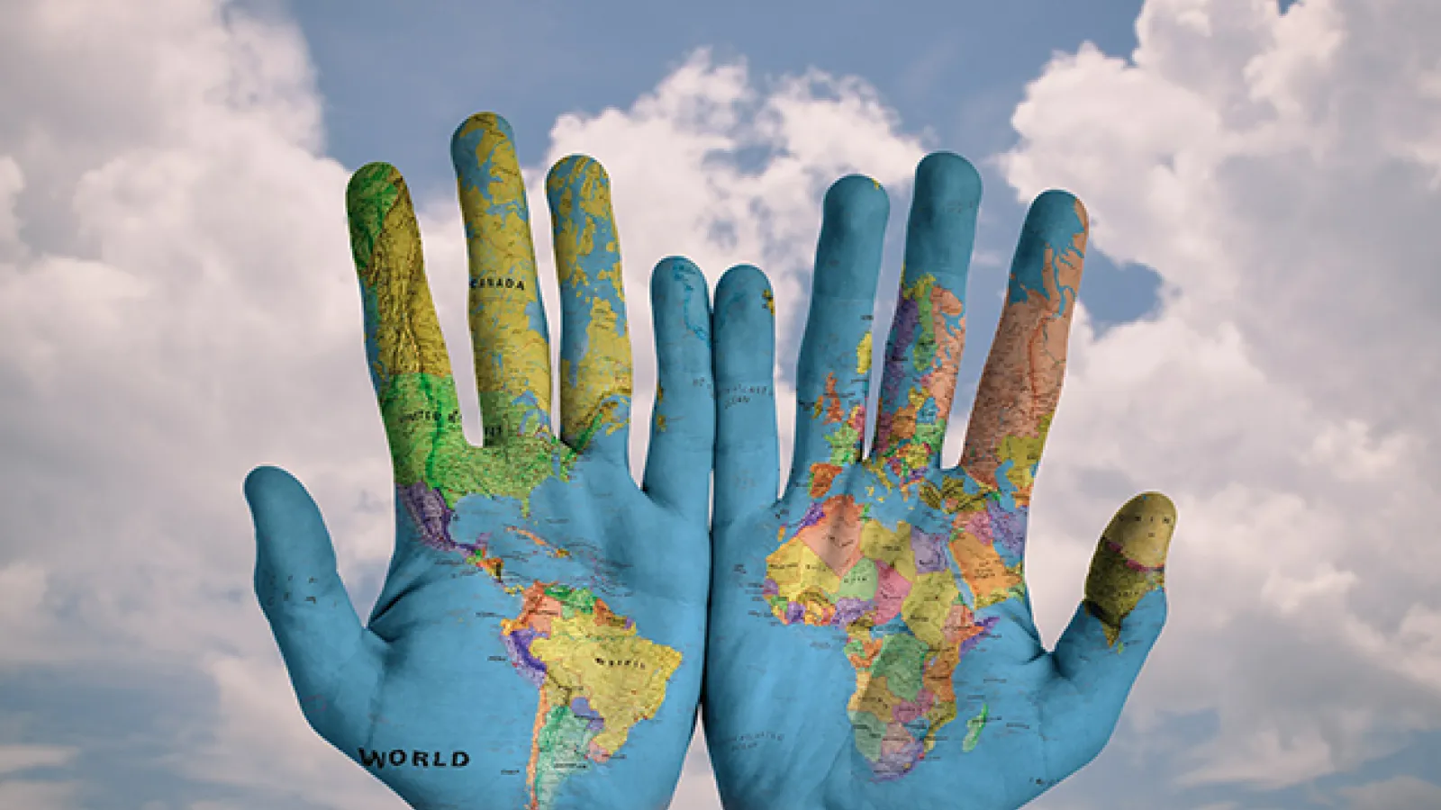 Two hands with the world map painted on them, sky in the background