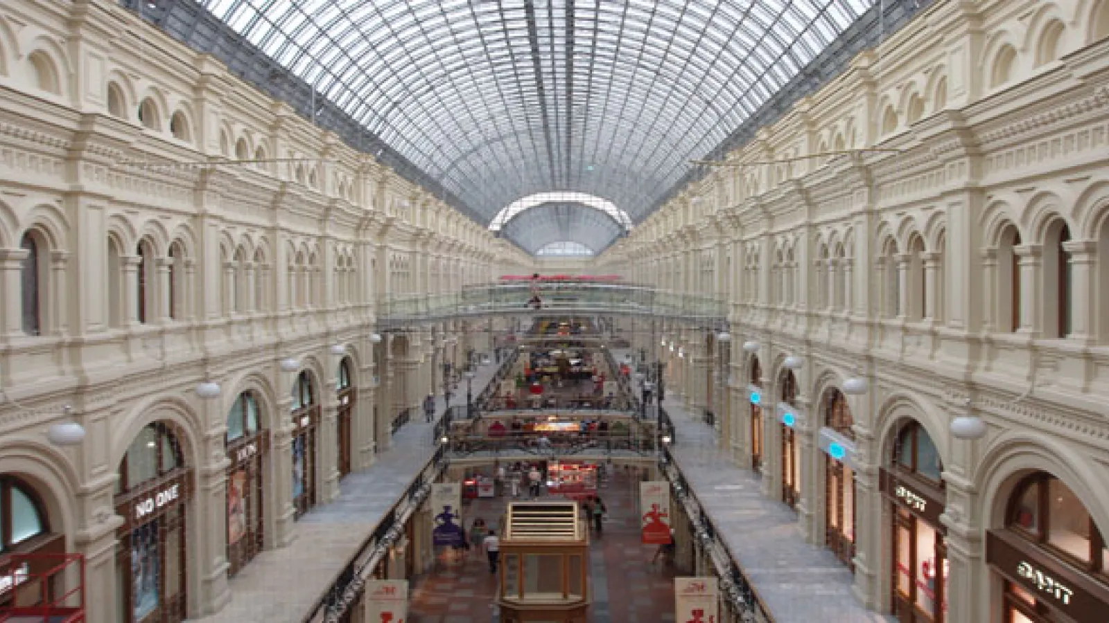 Aerial shot looking down long corridor of a shopping mall with arches and windows.  