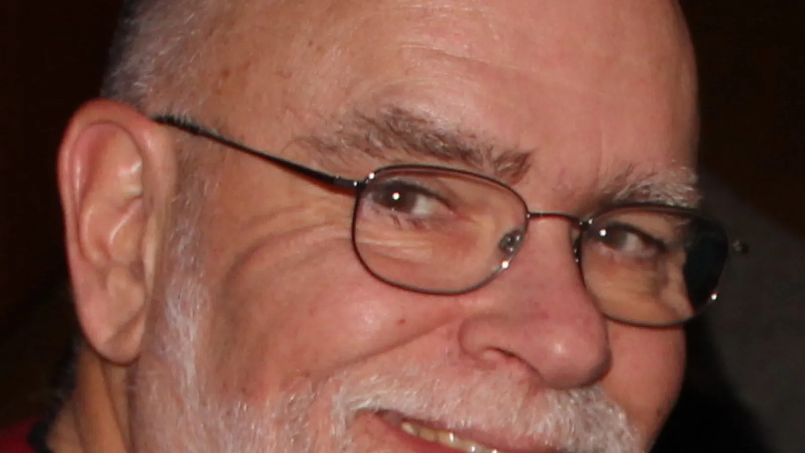 Close up photo of man's face with a beard and wearing glasses
