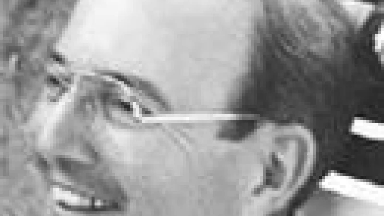 Close of man's face, smiling, wearing glasses