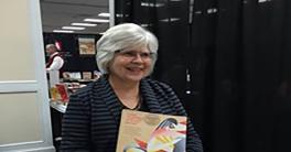 A woman standing behind a table covered with brightly colored books