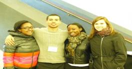 Three female and one male student standing next to each other smiling