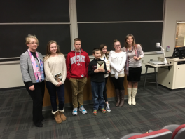Heritage Speakers at K12 Olympiada 7 people standing and smiling in front of room, two holding up book prizes