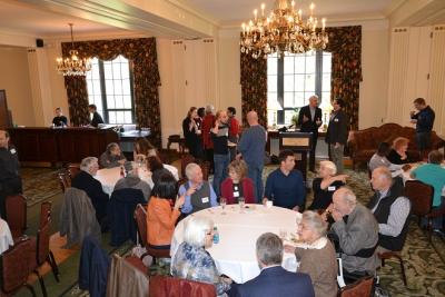 People sitting at tables and standing talking to each other in a large room