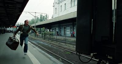 Man running to a platform to catch a leaving train