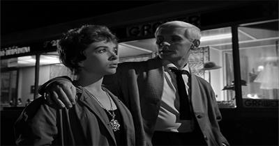 From the Film "Innocent Sorcerers" A man with his arm around a woman's shoulder walking down the street
