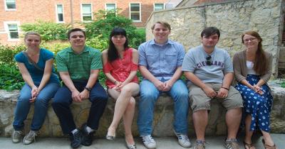 Students sitting on a ledge with garden in background