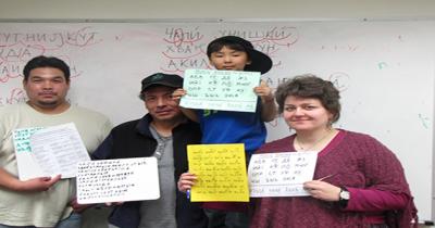 Learning Alutiiq and Slavonic Two men, a young boy, and woman standing holding signs with printing