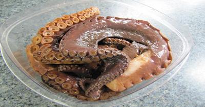 Plastic container filled with raw octopus tentacles