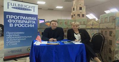 Table with a man and women sitting behind it, large banner on left advertising the Fulbright Program