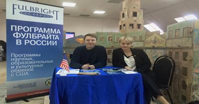 Eric at a Fulbright Table Table with a man and women sitting behind it, large banner on left advertising the Fulbright Program