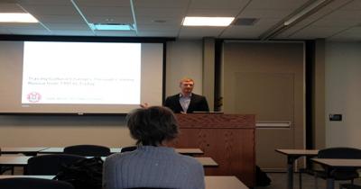 PhD Student Justin Wilmes Delivering Lecture Man standing looking at podium speaking in front of a classroom