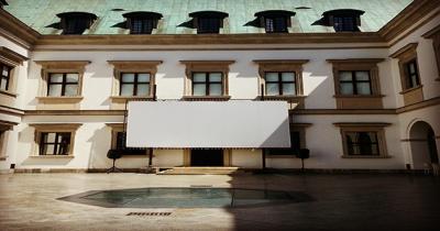 A white film screen hanging from the wall of a building in a courtyard