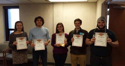 Five students standing in row each holding a certificate