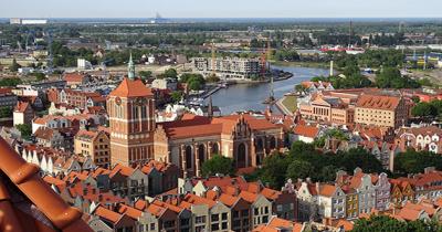 Aerial view of city with red brick buildings with tile roofs, and a river in the background winding through the city