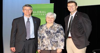 Lecture on the Crisis in Ukraine with the Columbus Council on World Affairs Two men and woman standing shoulder to shoulder facing the camera in front of a blue and green background