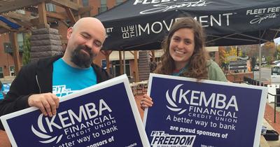 CSEES MA Students Katie McAfee and Justin Ciucevich at the Fit For Freedom 5K A man and a woman standing next to each other holding blue signs