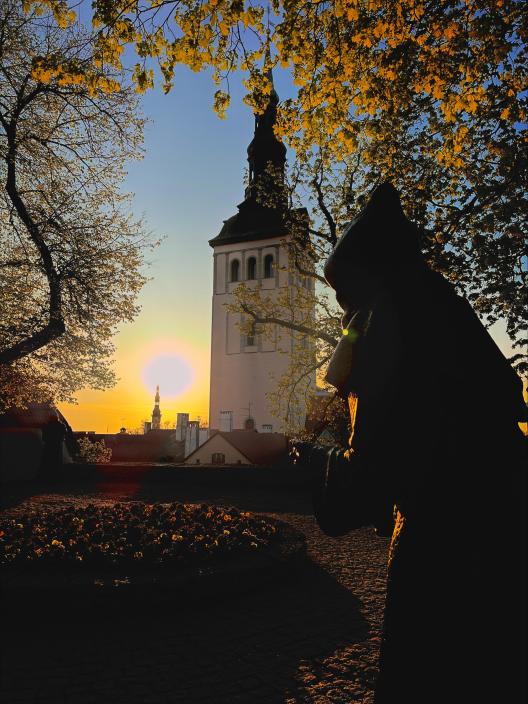 Statue of a monk in front of a sunset in Tallinn, Estonia