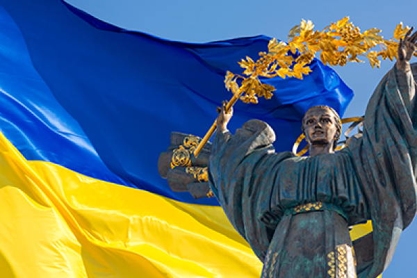 Monument of Independence of Ukraine in front of the Ukrainian flag.