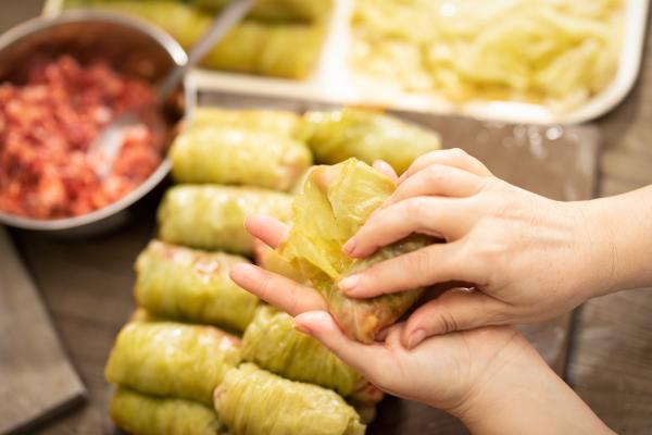 A pair of hands rolling and preparing Ukrainian Holubtsi, a type of cabbage leaf roll that is stuff with meat. 