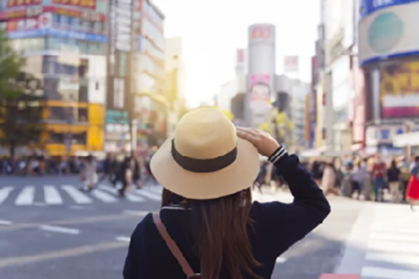 girl wearing a straw hat looking out at the Shibuya Scramble Crossing