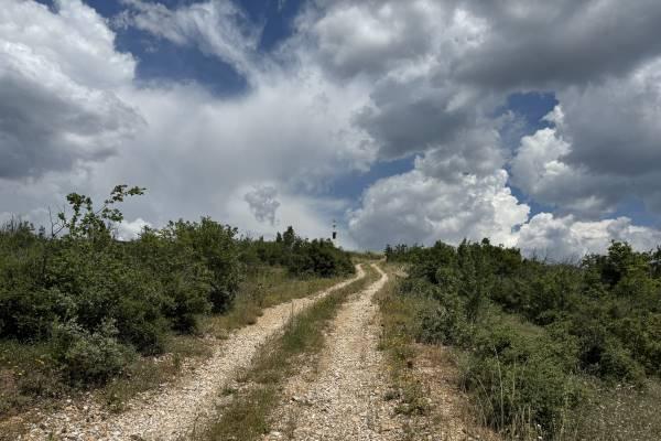 A dirt road leads uphill to dramatic clouds in Bulgaria