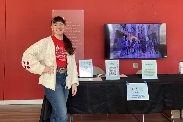 Alexis Voisard poses in front of the conference registration table at the Lessons from Abroad Conference