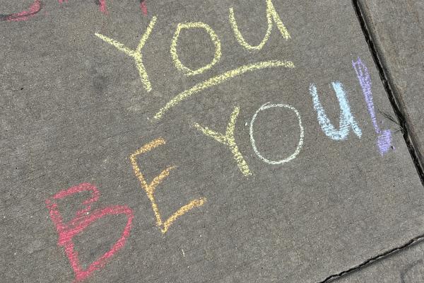 Rainbow chalk writing on the sidewalk that read "You be you!"