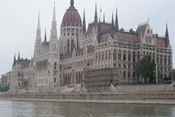 Long Gothic building with red tile roof on the banks of a river