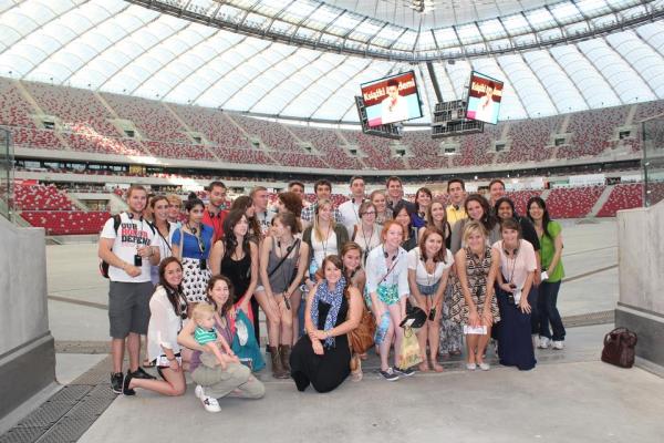 Large group of people standing between the stands in a stadium in rows next to each other