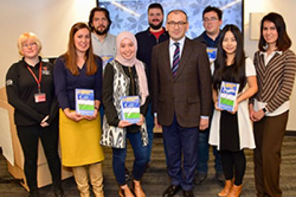 Uzbek language class with Ambassador of Uzbekistan People standing should to shoulder in front of a large screen